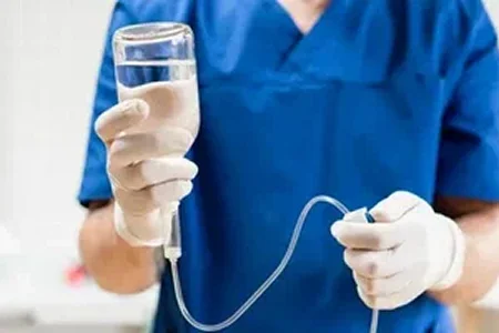Врач в синей форме держит капельницу